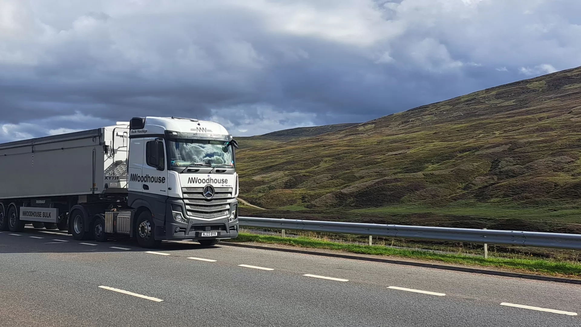 White Woodhouse Transport DAF truck pulled over on the road side in a lay by with rolling hills in the background.