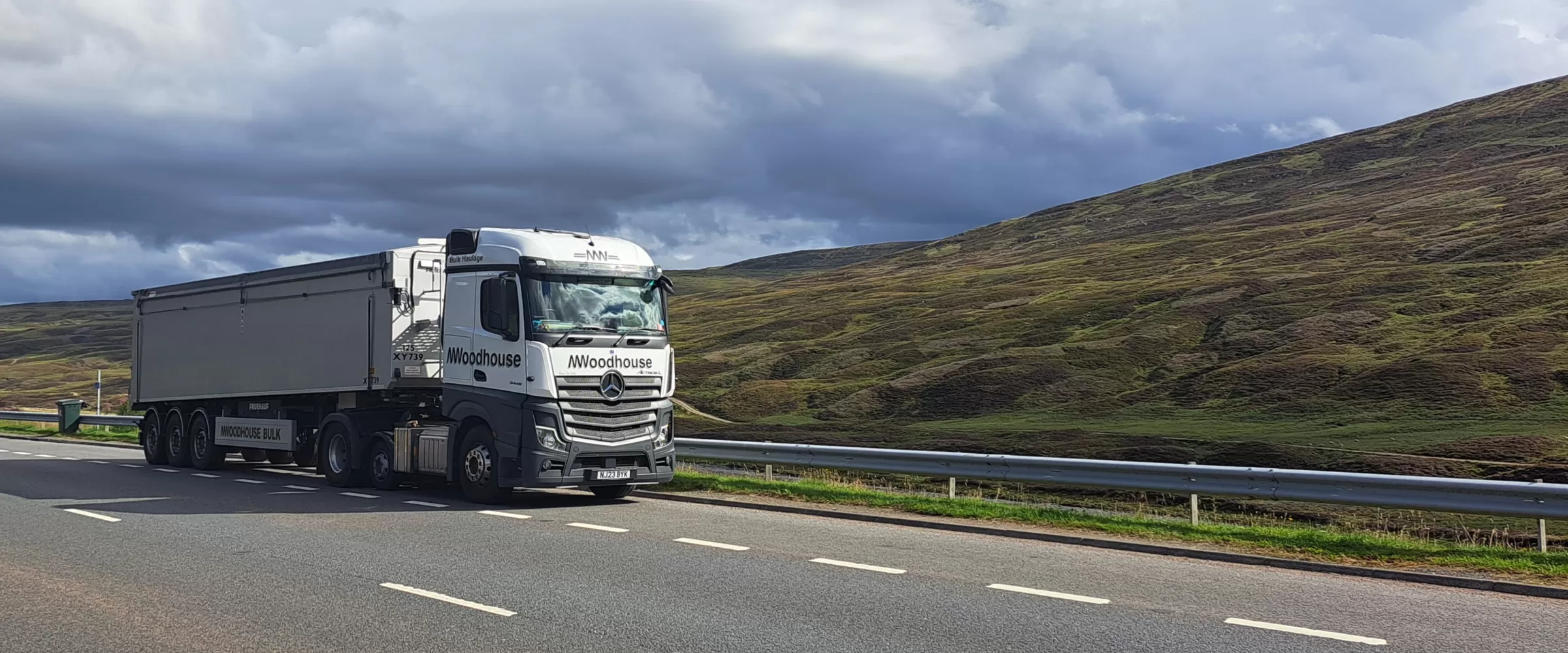 White Woodhouse Transport DAF truck pulled over on the road side in a lay by with rolling hills in the background.